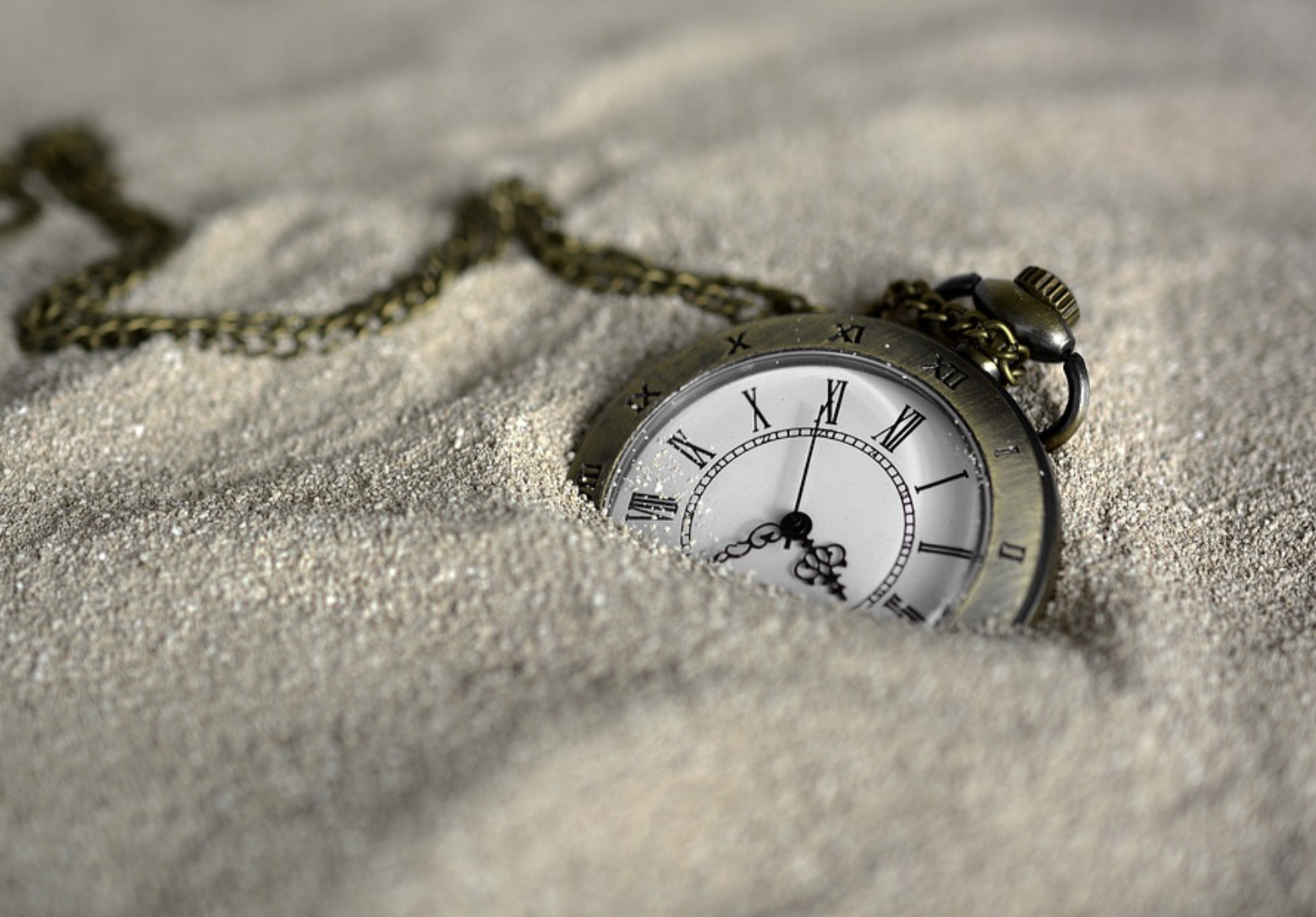 a pocket watch in some sand